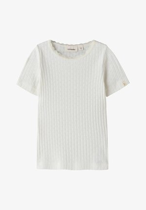 Wit gebreid shirt met korte mouwen, een klein oogjespatroon en kanten rand langs de ronde halslijn, gelabeld "Lil’ Atelier."
