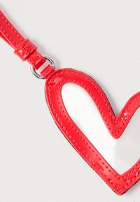 Porte-clés en cuir verni rouge brillant en forme de cœur avec des bords cousus, attaché à une lanière assortie sur fond clair.