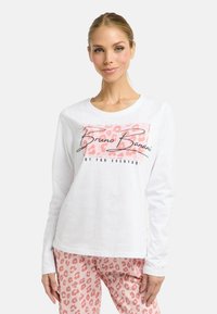 Weißes Langarmshirt mit pinkem Leopardenmuster und schwarzem Text. Kombiniert mit pinken Hosen mit passendem Leopardenmuster.