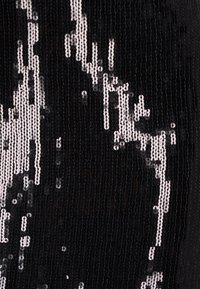 Fekete szövet ezüst paillettes díszítéssel hullámos mintában, amely texturált felületet és tükröződésű minőséget hoz létre.