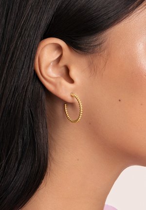 Goldene Creolen mit einem strukturierten Design, das kleine, gleichmäßig verteilte Perlen zeigt. Sie sind kreisförmig und werden am Ohrläppchen befestigt.