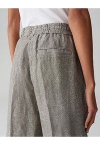 Linnen broek in lichtgrijs met een elastische tailleband en een achterzak. De stof heeft een gestructureerde, licht gedrapeerde uitstraling.