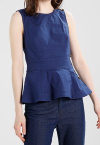 Marinblå peplumtop i lättviktig tyg, med rund halsringning, ärmlös design och sidoknappar.