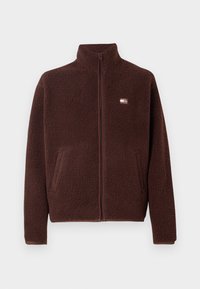 Jachetă din fleece maro cu guler înalt, închidere cu fermoar, buzunare laterale și un mic patch branduit pe piept. Material texturat, moale.
