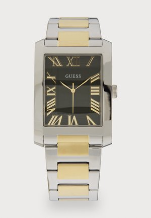 Prostokątny zegarek Guess z czarną tarczą i cyframi rzymskimi, srebrną metalową kopertą oraz dwukolorową bransoletą z metalu w odcieniach srebra i złota.