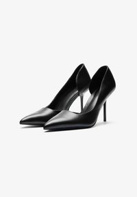 Zapatos de tacón alto negros de cuero con punta afilada, diseño elegante y silueta curva. Textura suave y tacón de aguja esbelto.