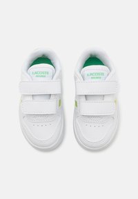 Baskets blanches avec des accents verts, en matériau synthétique, dotées d'une fermeture Velcro et de détails perforés pour la ventilation.