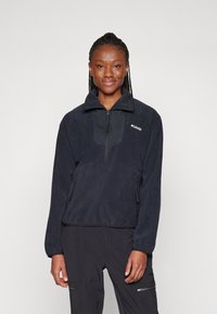 Donkerblauwe fleece trui met een kwart-rits aan de voorkant, hoge kraag en twee ritszakken aan de zijkanten, met een geometrisch paneelontwerp.