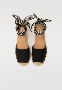 Sorte espadrille sandaler i stoff med vevde jute-detaljer, åpen tå og mønstrede ankelbånd. Flat såle med minimal tekstur.