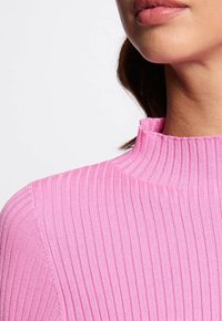Maglione rosa a coste con colletto alto e tessuto testurizzato. Il design presenta righe verticali e una silhouette aderente.