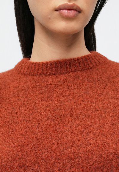 Roostevärvi kootud kampsun soonikkoega ümmarguse kaelusega. Kangas on pehme ja karvane, millel on tekstuuriga pind ja kerge läige.