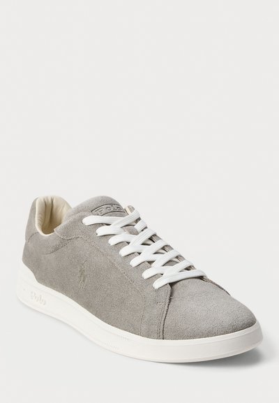 Grey suede low-top sneaker with white laces and sole, featuring subtle embossed logo on the side and tongue.