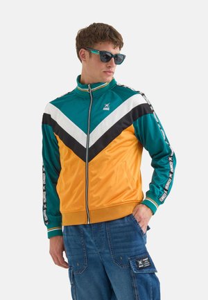 Trackjakke med lynlås, prydet med et farveblokdesign i teal, sort, hvid og orange, fremstillet af glat stof med logo-detaljer.