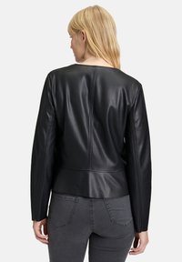 Svart skinnjacka med en figurnära design, långa ärmar och en något kortad bakdel. Innehåller sömdetaljer och en slät yta.