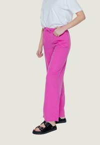 Pantaloni di lino rosa con una vestibilità morbida e vita elastica, abbinati a sandali neri con dettagli in fibbia.