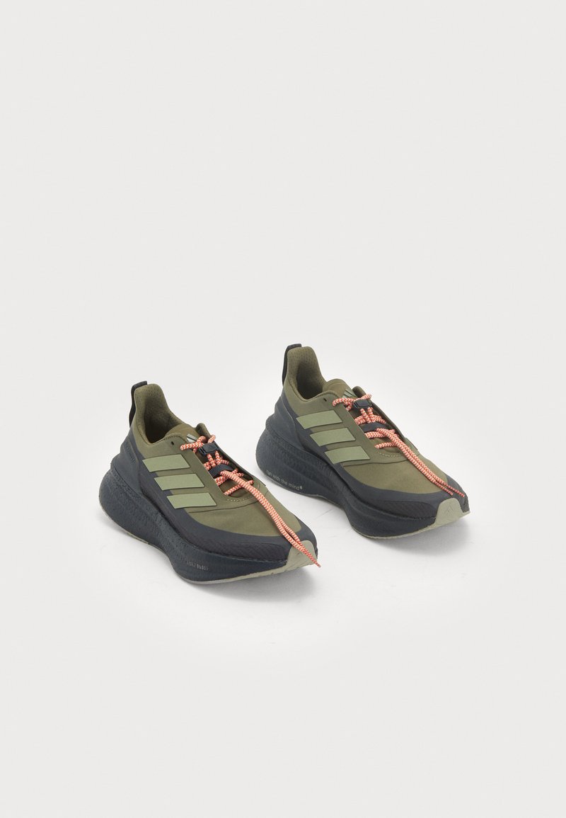 Olivgrüne Sportschuhe mit schwarzen Akzenten, dicken Sohlen und orangenen Schnürsenkeln. Verfügt über drei grüne Streifen an der Seite und eine strukturierte Profilsohle.