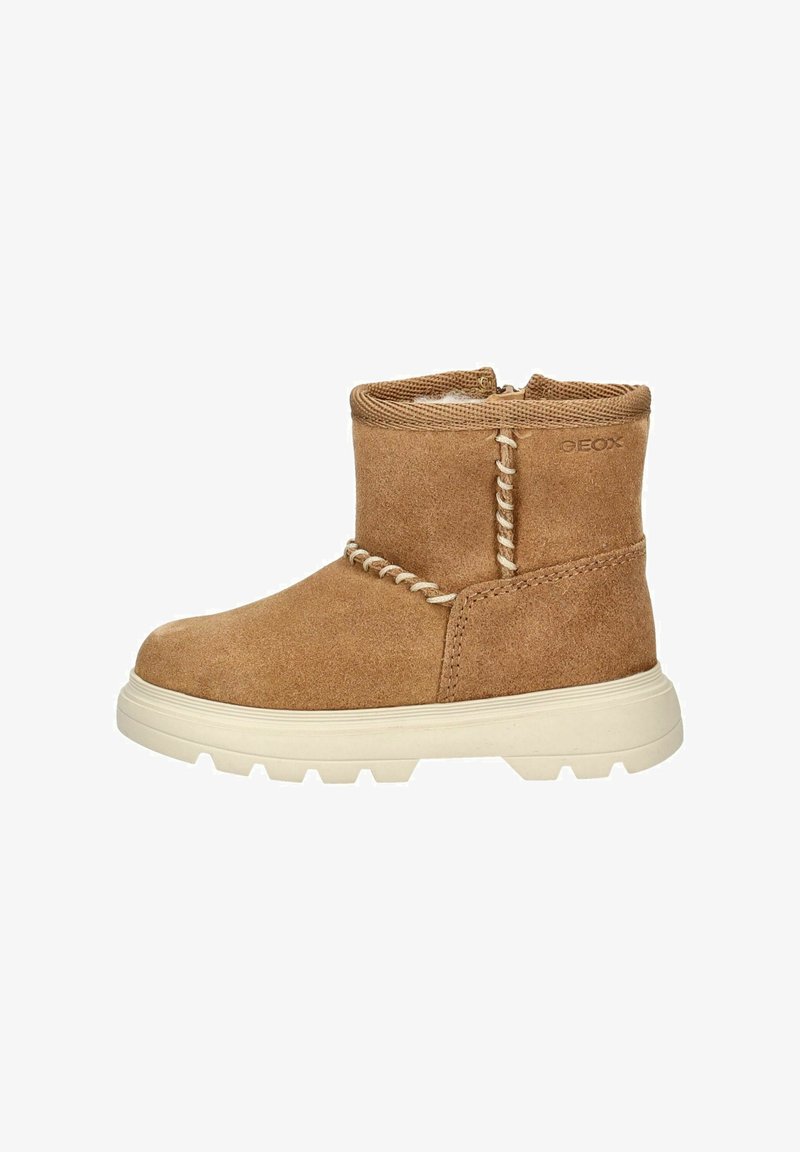 Botín de tobillo de ante marrón con detalles de costura, forro texturizado y suela de goma blanca. Presenta una punta redondeada y un diseño de perfil bajo.