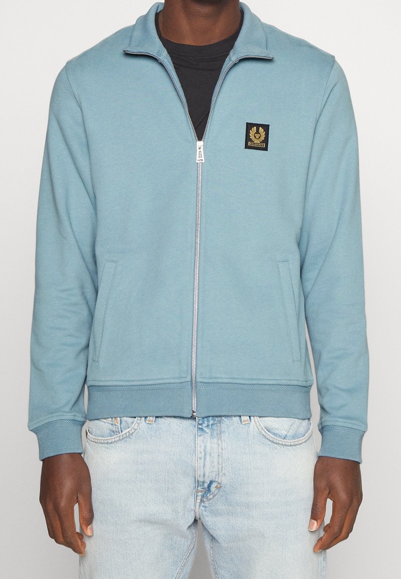 Sudadera con cremallera en azul claro, mezcla de algodón; cuenta con bolsillos laterales y puños de canalé. Parche del logo negro en el lado izquierdo del pecho. Ajuste casual.