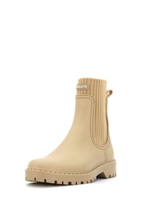 Bota de tobillo de goma beige con lado elástico acanalado, punta redondeada, suela texturizada y una lengüeta en la parte trasera para facilitar el uso.