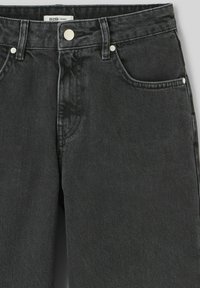 Jeans en denim noir au design ample, dotés d'une fermeture à bouton, de cinq poches et d'un tissu doux et texturé. Fini légèrement décoloré.