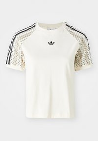 Vit bomulls-T-shirt med svarta och gräddfärgade randiga axelpaneler, rund halsringning och liten broderad logotyp på bröstet.