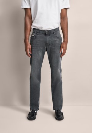 Graue Denim-Jeans mit geradem Schnitt, ausgestattet mit einem klassischen Fünf-Taschen-Design und dezenten Ausbleichungen. Kombiniert mit schwarzen Schuhen und einem weißen T-Shirt.