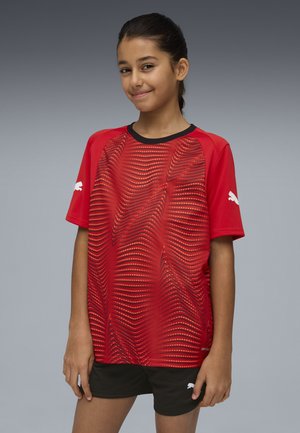 Rød sportstrøje med korte ærmer og bølgemønster, med sorte detaljer og hvide Puma-logoer på ærmerne. Kombineret med sorte shorts.