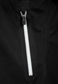 Svart tyg med en framträdande vit dragkedja med en svart dragknapp, vilket framhäver kontrasten i färg och design.