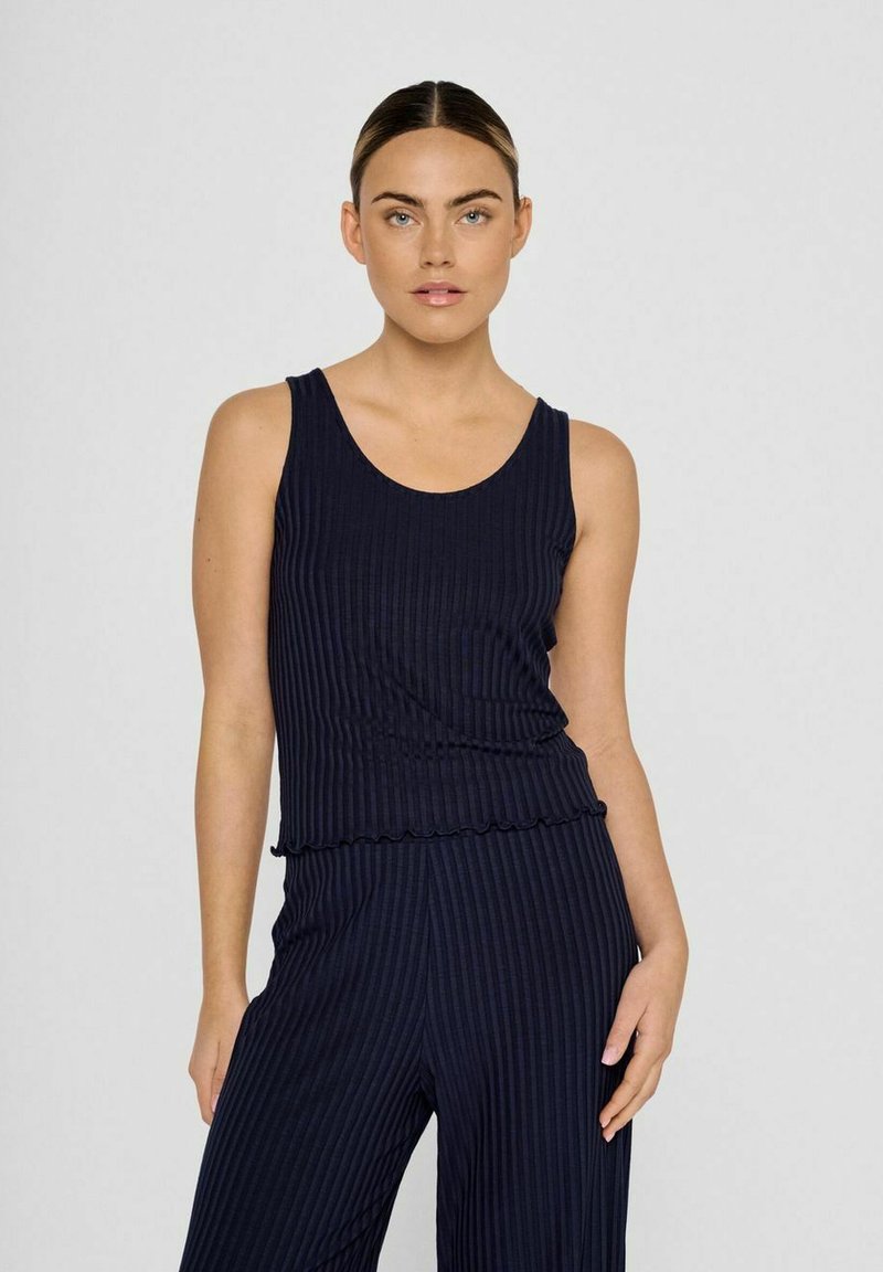 Navyblauwe ribbel tanktop met een geschulpte zoom, gecombineerd met wijde broekspijpen. De stof heeft een gestructureerde afwerking met verticale strepen.