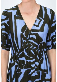 Robe texturée à manches courtes avec décolleté en V. Tissu bleu avec des motifs abstraits verts foncés. Détail de taille froncée.