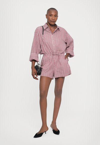 Red and white striped short romper with a collar, cinched waist, and long sleeves. Paired with black slingback shoes and a small black bag.