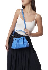 Borsa a secchiello azzurro chiaro con finitura texture, tracolla regolabile, chiusura a coulisse e dettagli in metallo argentato.