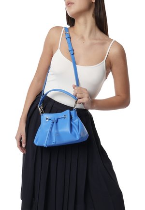 Sac à main en forme de seau bleu clair avec une finition texturée, une bandoulière réglable, une fermeture à cordon de serrage et des accents en métal argenté.