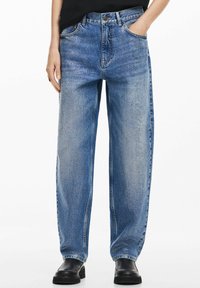 Ljusblå denimjeans med avslappnad passform, fem fickor och en urtv�ättad textur. Utrustad med knapp- och dragkedjestängning, bärs med svarta skor.