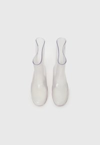 Bottes transparentes jusqu'aux genoux avec une finition lisse et brillante, conçues avec un bord supérieur ondulé et une pointe renforcée, présentant un accent violet subtil.
