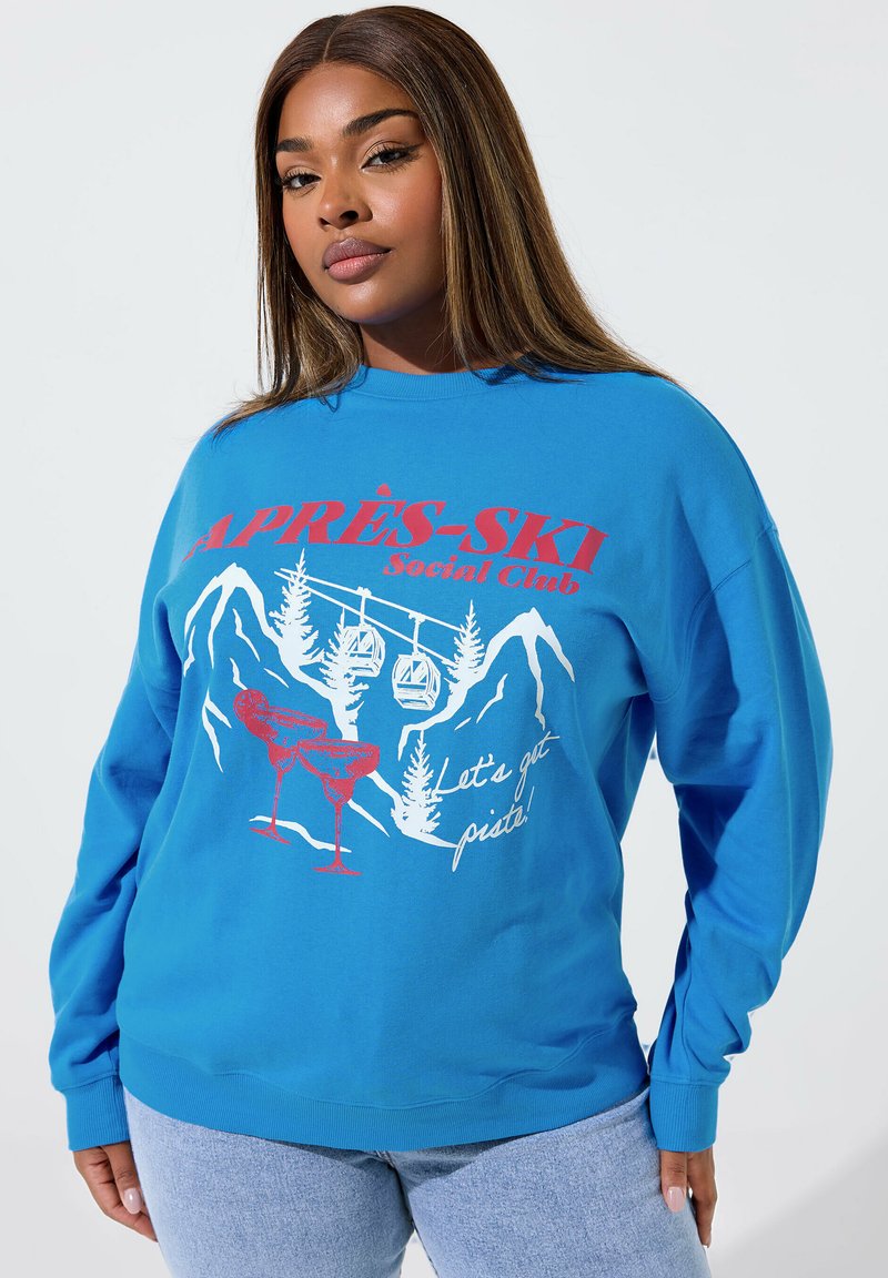 Blaues Sweatshirt mit langen Ärmeln, das ein grafisches Design von Bergen, Skiliften und Cocktails in Rot und Weiß zeigt.