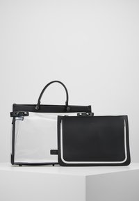 Borsa tote in PVC trasparente con dettagli e manici in pelle nera, abbinata a una pochette in pelle nera con dettagli a contorno bianco.
