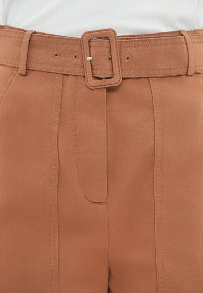 Pantalons en tissu marron avec une large ceinture, présentant une boucle carrée et des coutures contrastées. Comprend deux poches latérales et une fermeture éclair.