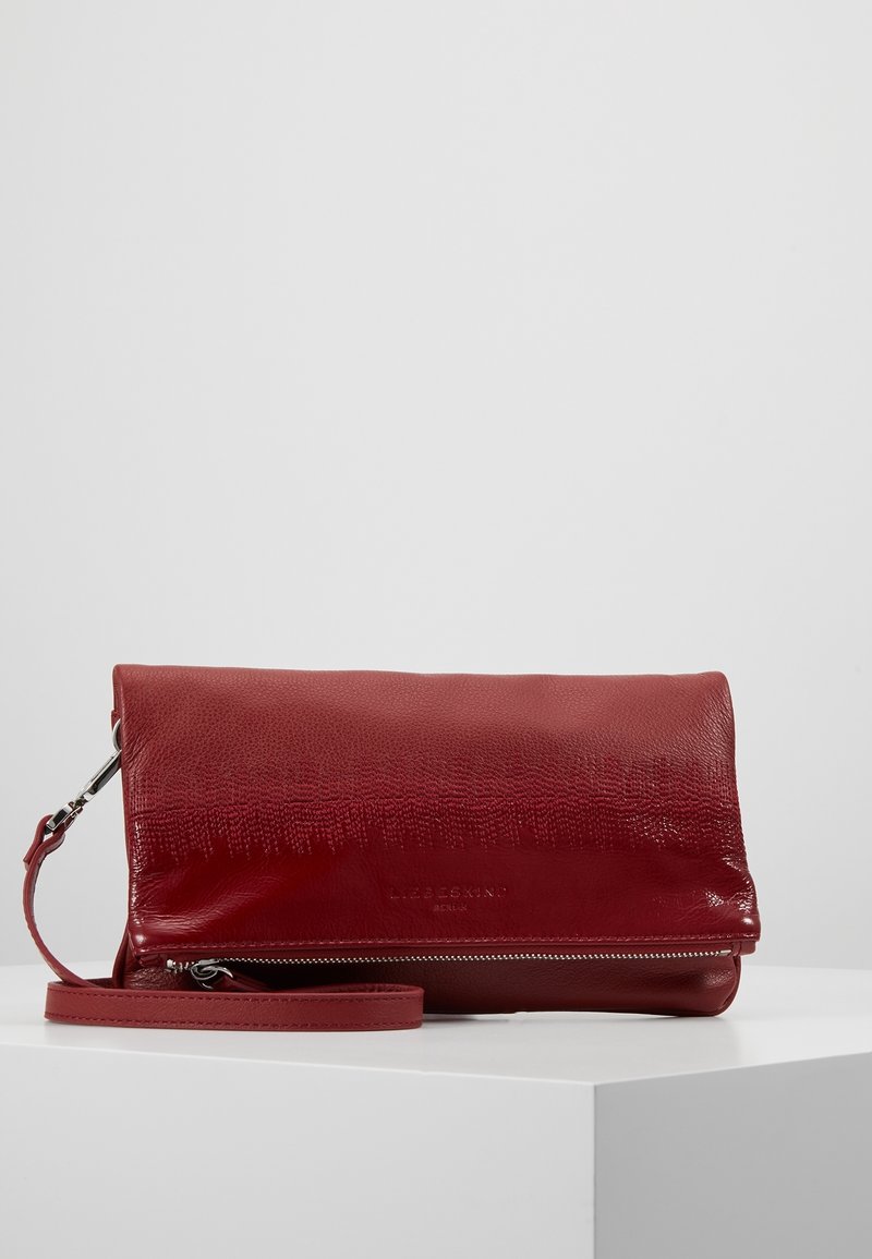 Červená kožená kabelka přes rameno s texturovaným povrchem, překlopným víkem a odnímatelným popruhem; obsahuje stříbrný zip a detail s logem.