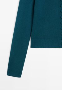 Turqoise gebreid vest met een rechte snit, lange mouwen, geribbelde manchetten en een knoopsluiting aan de voorkant met textuurrijke bobbelaccenten.