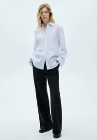 Light blue striped shirt with a button-up design, long sleeves, paired with black wide-leg trousers and black shoes. Simple, classic style.