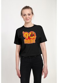 Sort t-shirt med et farverigt grafik af tallet '90' og ordet "BABY", samt en karakterillustration. Korte ærmer, afslappet skæring.