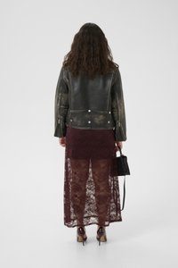 Μαύρο δερμάτινο μπουφάν με υφή, συνδυασμένο με μπορντώ δαντελένια maxi φούστα. Το σύνολο ολοκληρώνεται με μια μαύρη τσάντα και γυαλιστερές γόβες.