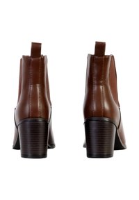 Bottines en cuir synthétique marron avec un bout arrondi, des panneaux latéraux élastiques et un talon empilable. Comprend une languette à l'arrière.