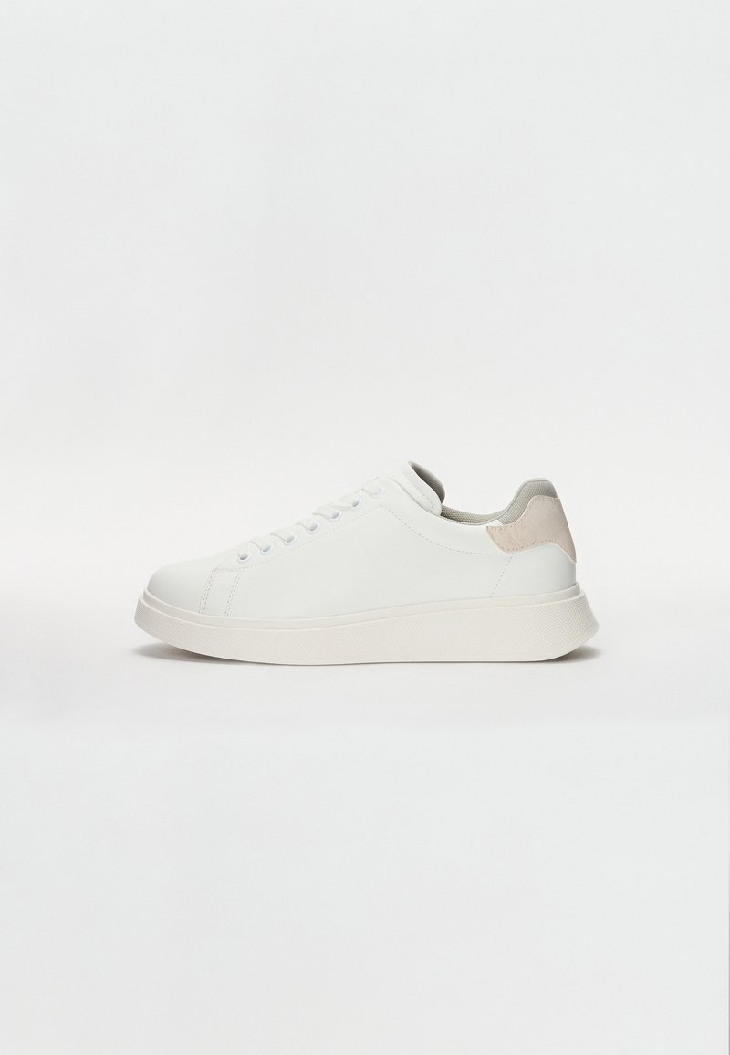 Fehér sneaker sima szintetikus felsőrészel, kerek orral, lapos fűzőkkel és kontrasztos bézs sarkú akcentussal. Vastag gumi talp, mely textúrázott tapadást biztosít.