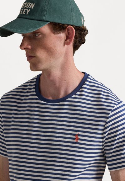 Tume sinise ja valge triibuline T-särk, millel on ümmargune kaelus. Vasar aeg on väike punane nüansiline logo vasakul rinnal. Puuvillane kangas.