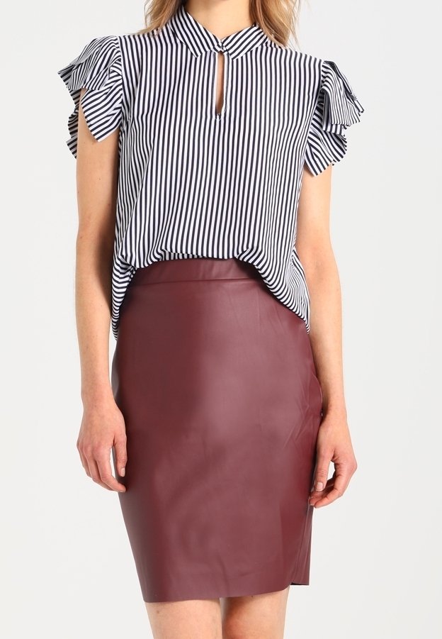 Randig blus med volang ärmar och nyckelhålsutringning; kombinerad med en figurnära bordeauxfärgad läderskjol. Söld väv, skräddarsydd design.