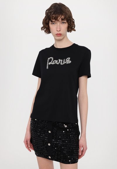 Schwarzes Baumwoll-T-Shirt mit Rundhalsausschnitt, verziert mit einem Strass-Design "Paris". Kombiniert mit einem schwarzen Pailletten-Minikleid mit dekorativen Knöpfen.