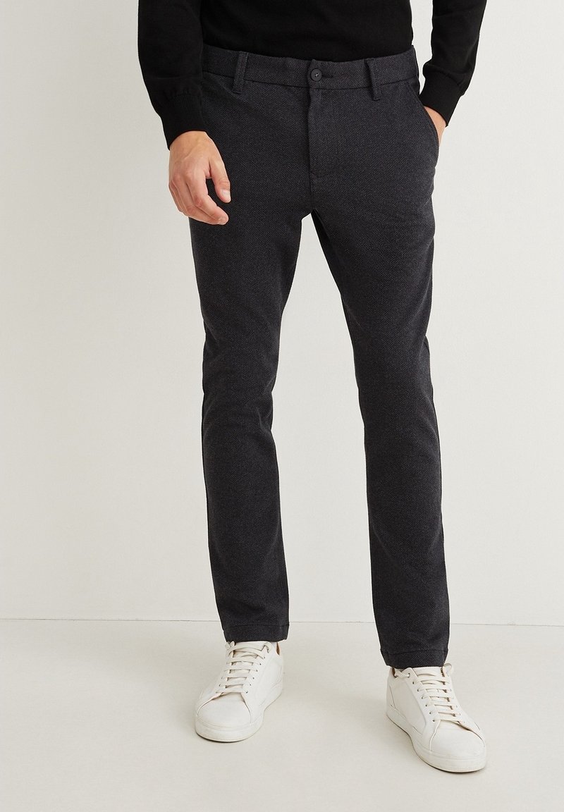 Tmavě šedé kalhoty s jemnou texturou a rovnými nohavicemi, doplněné bílými teniskami. Dvě přední kapsy a zapínání na knoflík.