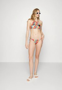 Spalvingas bikini rinkinys su kaklo surišimu, kurio viršus puoštas banguotais raštais įvairių spalvų ir animacinio akių motyvu. Bikini surišamas šonuose.